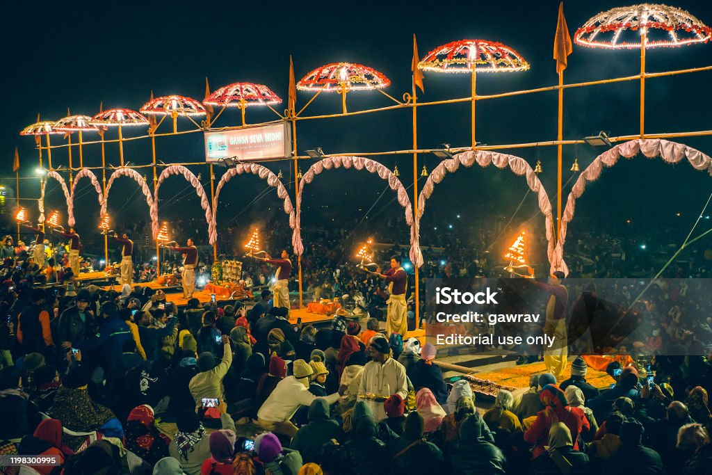 Varanasi, Uttar Pradesh, India - December 26, 2019: A crowd of people gathers on the bank of river Ganga to take part in the Aarti ritual. Hindu Pandits of Varanasi perform the Ganga Aarti ritual every evening for one hour from 6 pm onward at Dashashwamedh Ghat.